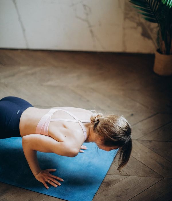 Woman in a peaceful yoga pose in a warmly lit room.